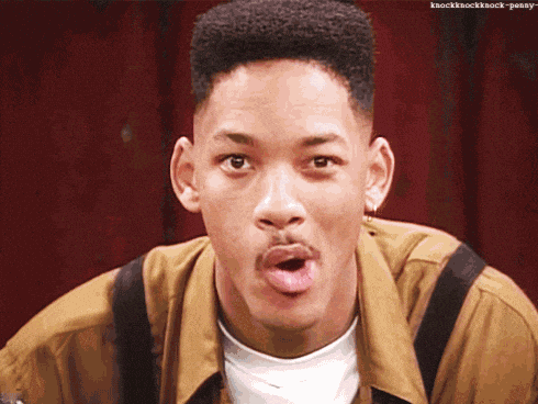 Will Smith making a funny face as he pulls a magnifying glass up to his eye to take a closer look